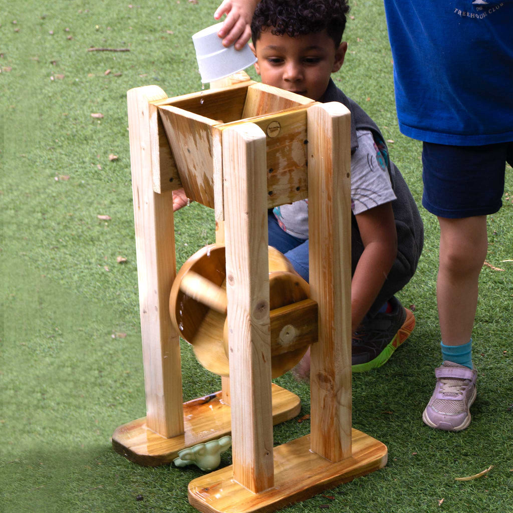 Child playing with a wooden toy on grass