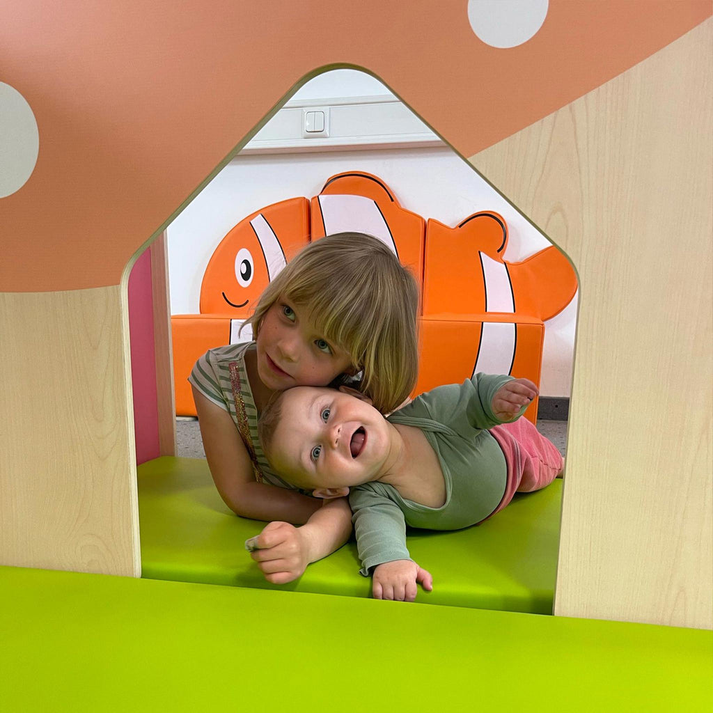 Two children playing inside a colorful playhouse with a clownfish design in the background.